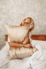 woman is hugging her pillow with beige silk pillowcase and looking happy