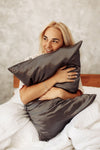woman is hugging a silk pillowcase and smiling